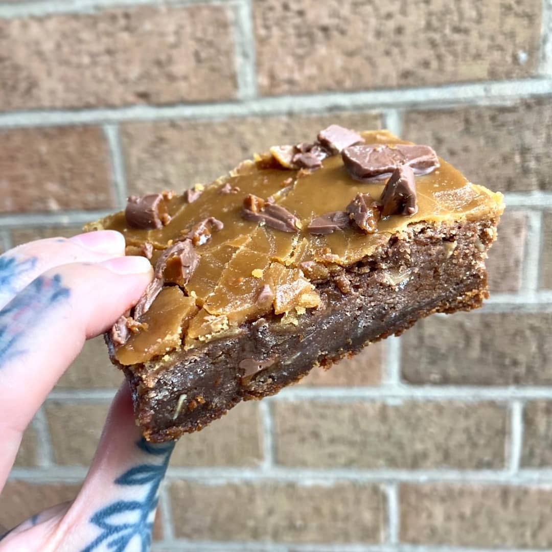 Caramel brownie held up against brick wall